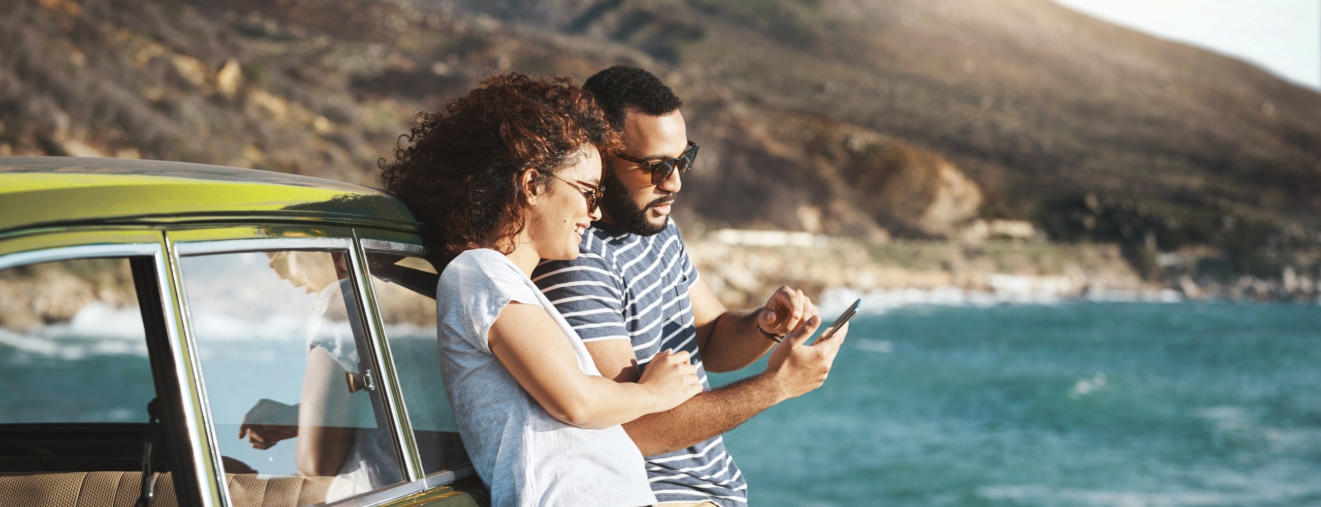 Shot of a young couple using a mobile phone on a road trip
